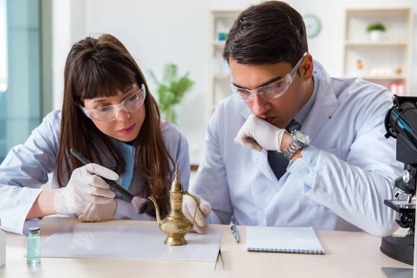 Two archeologists looking at ancient gold lamp