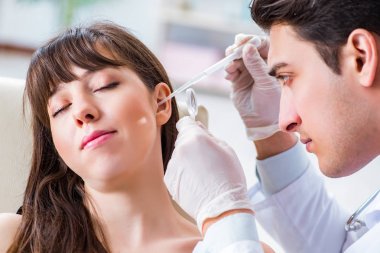 Doktor muayene sırasında hastaların kulaklarını kontrol ediyor.