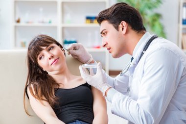 Doktor muayene sırasında hastaların kulaklarını kontrol ediyor.