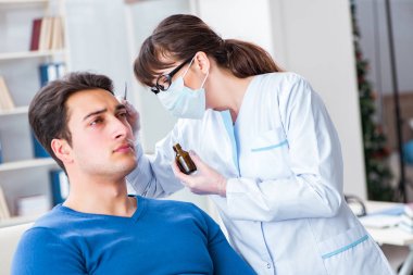 Doktor muayene sırasında hastaların kulaklarını kontrol ediyor.