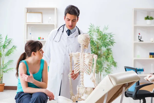 Doctor showing type of injury on skeleton to patient — Stock Photo, Image