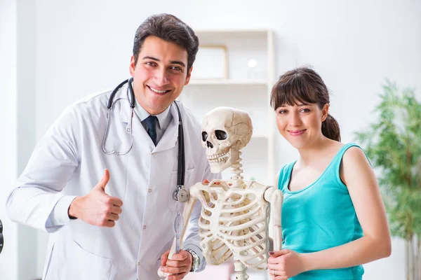 Doctor showing type of injury on skeleton to patient — Stock Photo, Image