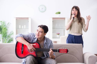 Genç bir aile evde şarkı söylüyor ve müzik çalıyor.