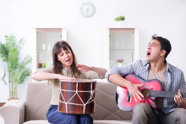 Genç bir aile evde şarkı söylüyor ve müzik çalıyor.