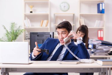 Meslektaşı meşgulken ofiste oyun oynayan adam.