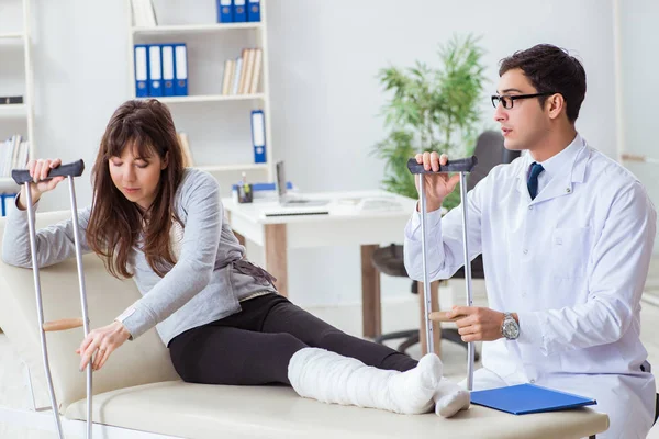 Médecin examinant patient avec jambe cassée — Photo