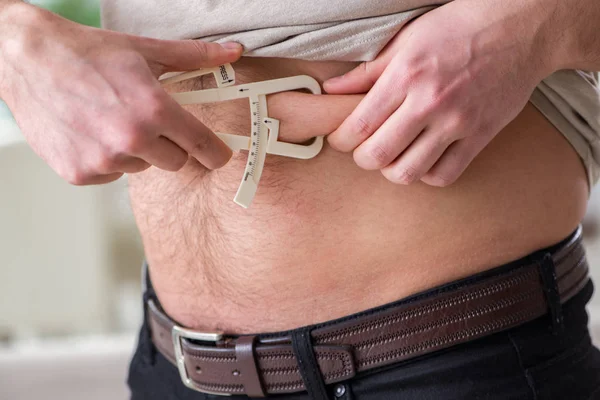 Hombre midiendo grasa corporal con pinzas — Foto de Stock