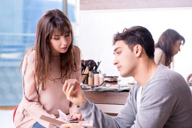 Güzellik salonunda güzel bir kadın için makyaj yapan adam.