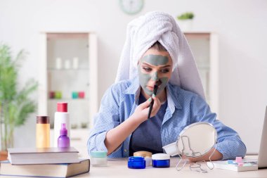 Kadın evde fırçayla kilden maske takıyor