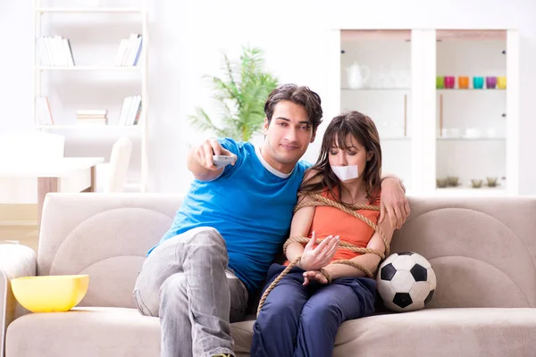 Hombre atando a su esposa para ver deportes de fútbol — Foto de Stock
