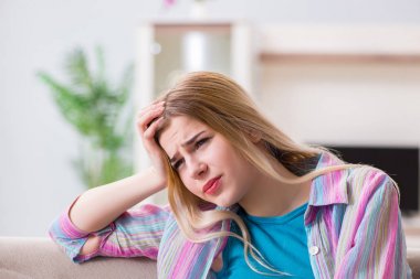 Evde acı çeken genç bir kadın.