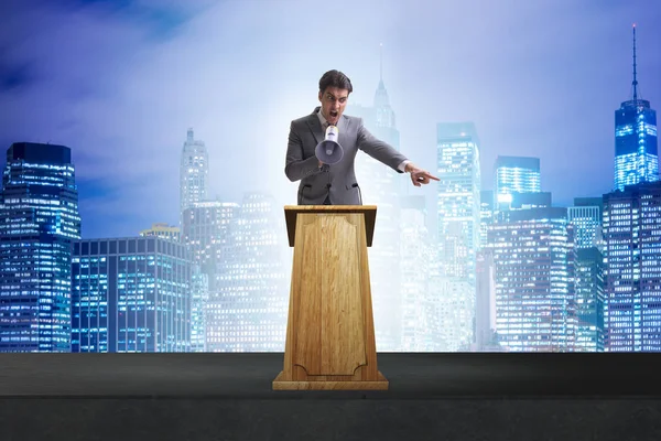 Hombre de negocios haciendo discurso en la tribuna en el concepto de negocio — Foto de Stock