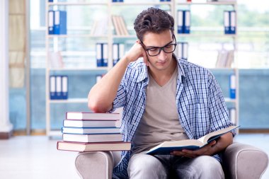 Öğrenci kitap okuyor ve kütüphanede sınavlara hazırlanıyor