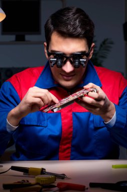 Bilgisayar uzmanı gece geç saatlerde bilgisayarı tamir ediyor.