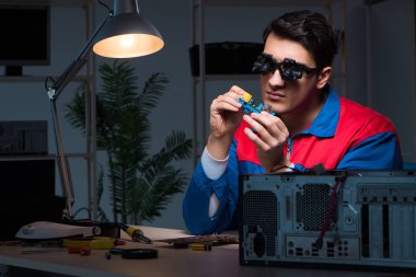 Bilgisayar uzmanı gece geç saatlerde bilgisayarı tamir ediyor.