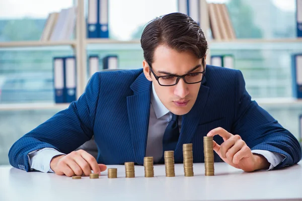 Businessman with stacks of coins in the office — Stock Photo, Image