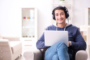 Genç yakışıklı adam kulaklıkla müzik dinliyor.
