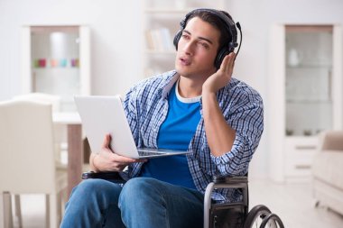 Tekerlekli sandalyede müzik dinleyen engelli adam.