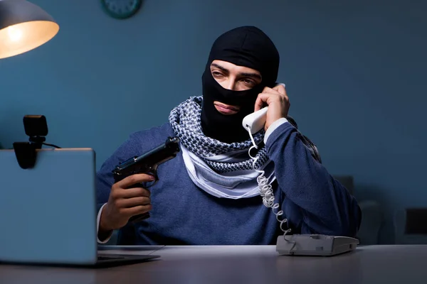 Terrorist burglar with gun working at computer — Stock Photo, Image