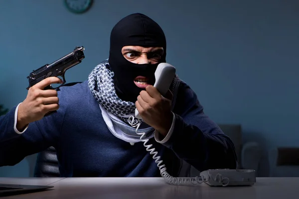 Terrorist burglar with gun working at computer