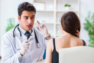 Doktor muayene sırasında hastaların kulaklarını kontrol ediyor.