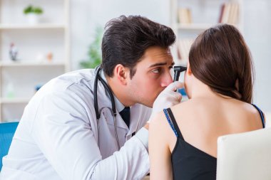 Doktor muayene sırasında hastaların kulaklarını kontrol ediyor.