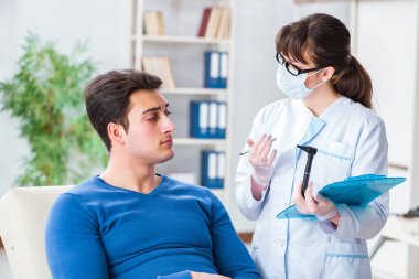 Doktor muayene sırasında hastaların kulaklarını kontrol ediyor.