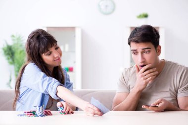 Genç bir aile evde kağıt oynuyor.