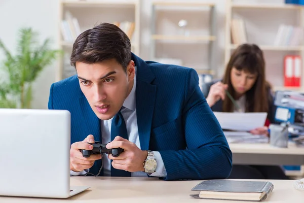 Man playing games in office while colleague is busy — Stock Photo, Image
