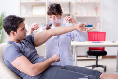 Doktor hastaların eklem esnekliğini gonimetreyle kontrol ediyor.