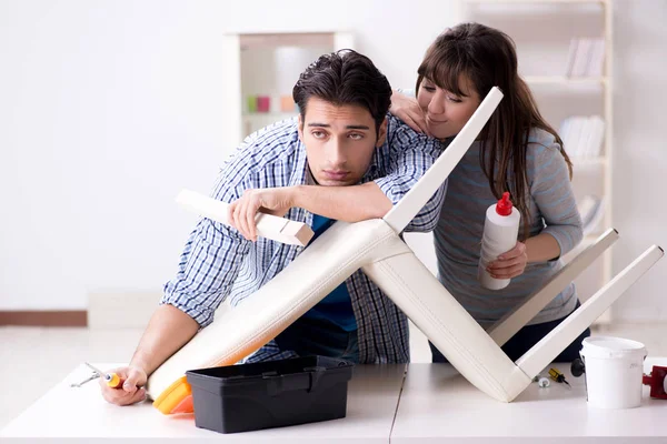 Ehefrau hilft Ehemann, kaputten Stuhl zu Hause zu reparieren — Stockfoto