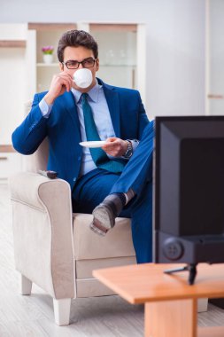 İş adamı ofiste televizyon izliyor.