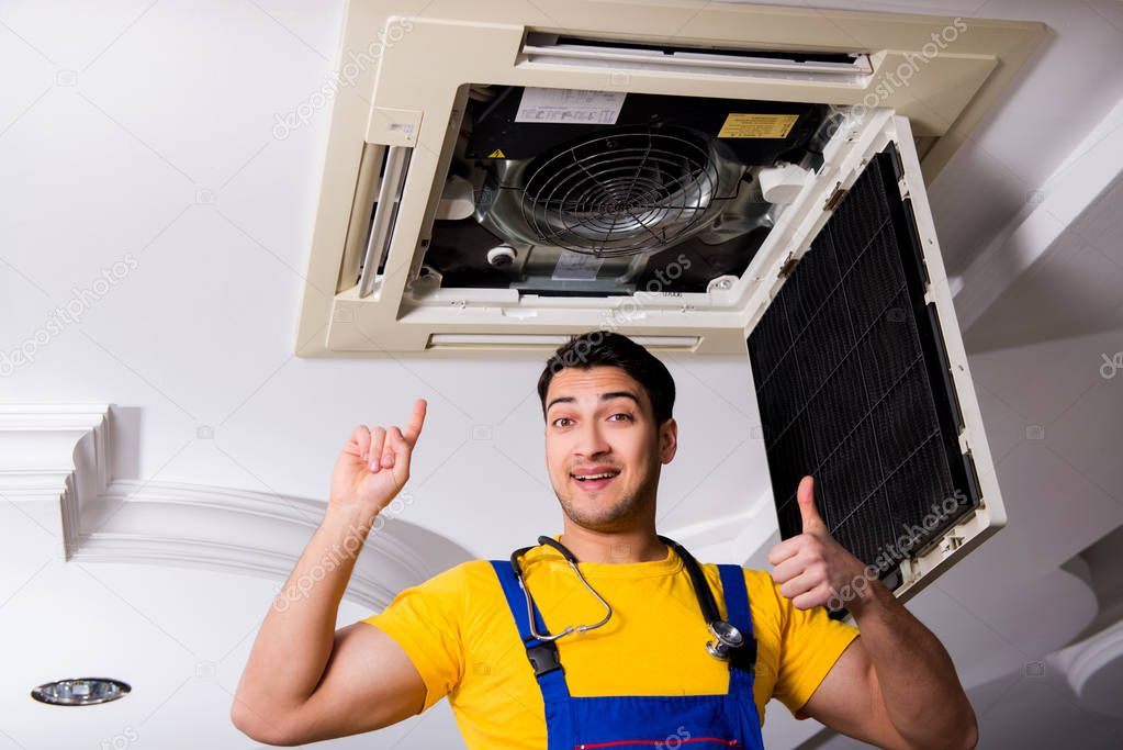 Repairman repairing ceiling air conditioning unit