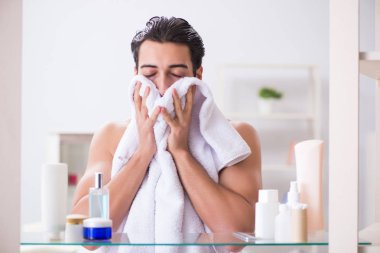 Genç adam banyoda çalışmak için hazırlanıyor.