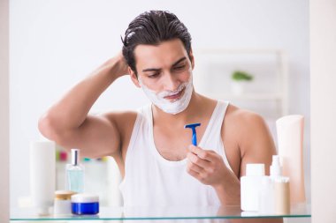 Genç yakışıklı adam sabah erkenden tıraş oluyor.