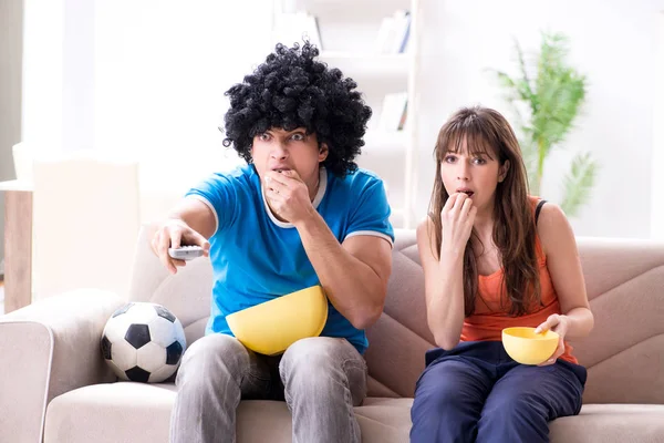Genç adam evde karısıyla futbol seyrediyor. — Stok fotoğraf
