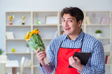 Çiçekçi asistanı bir demet çiçek veriyor.