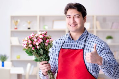 Çiçekçi asistanı bir demet çiçek veriyor.
