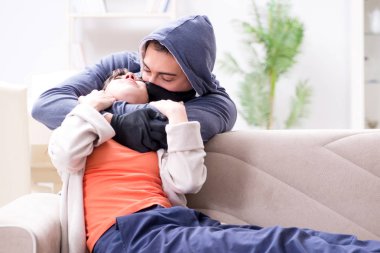 Silahlı bir adam evde genç bir kadına saldırıyor.