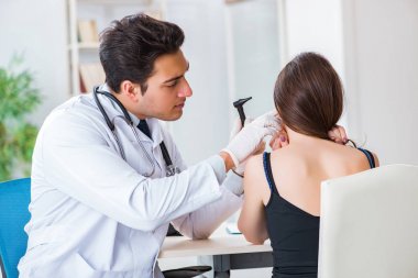 Doktor muayene sırasında hastaların kulaklarını kontrol ediyor.