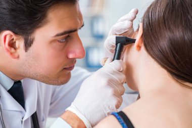 Doktor muayene sırasında hastaların kulaklarını kontrol ediyor.