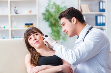 Doktor muayene sırasında hastaların kulaklarını kontrol ediyor.