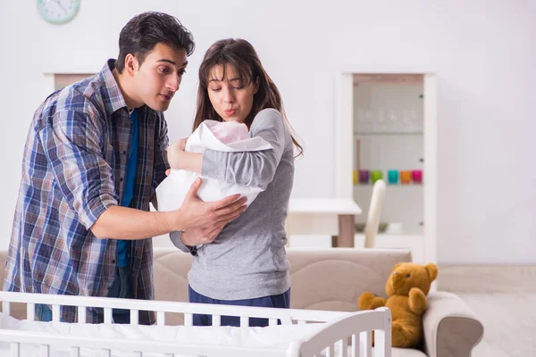 Young parents with their newborn baby near bed cot — Stock Photo, Image