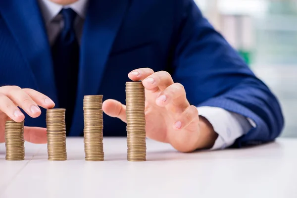 Businessman with stacks of coins in the office — Stock Photo, Image