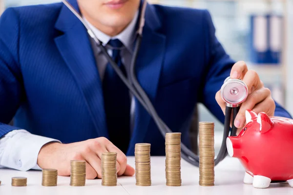 Empresario con pilas de monedas en la oficina — Foto de Stock