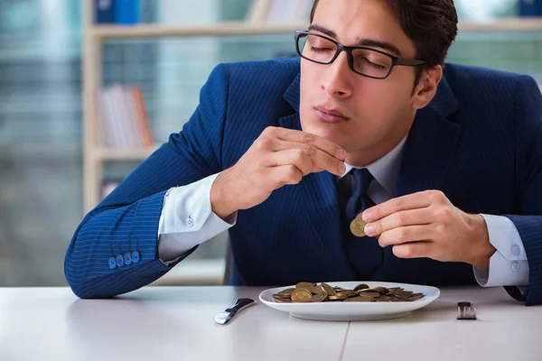 Забавный бизнесмен ест золотые монеты в офисе — стоковое фото