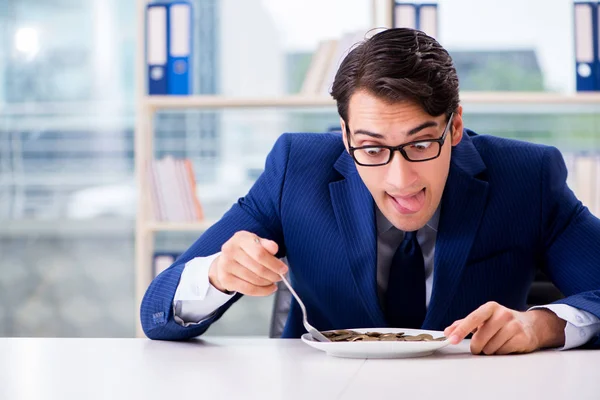 オフィスで金貨を食べる面白いビジネスマン — ストック写真
