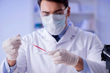 Laboratuvar asistanı hastanede kan örneklerini test ediyor.