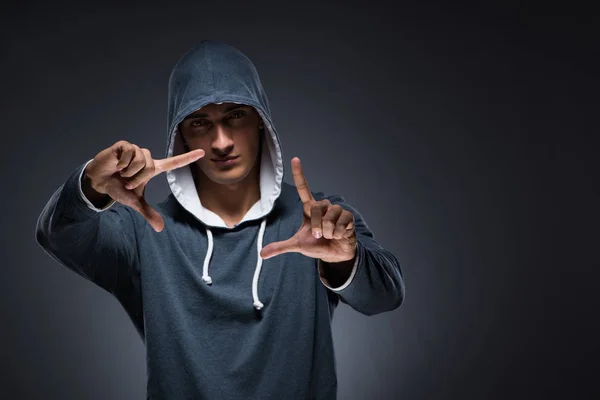 Egy fiatalember kapucnis pulóvert visel, virtuális gombokat nyomogat. — Stock Fotó