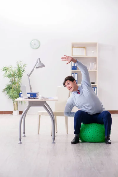 Employee exercising with swiss ball during lunch break — Stock Photo, Image